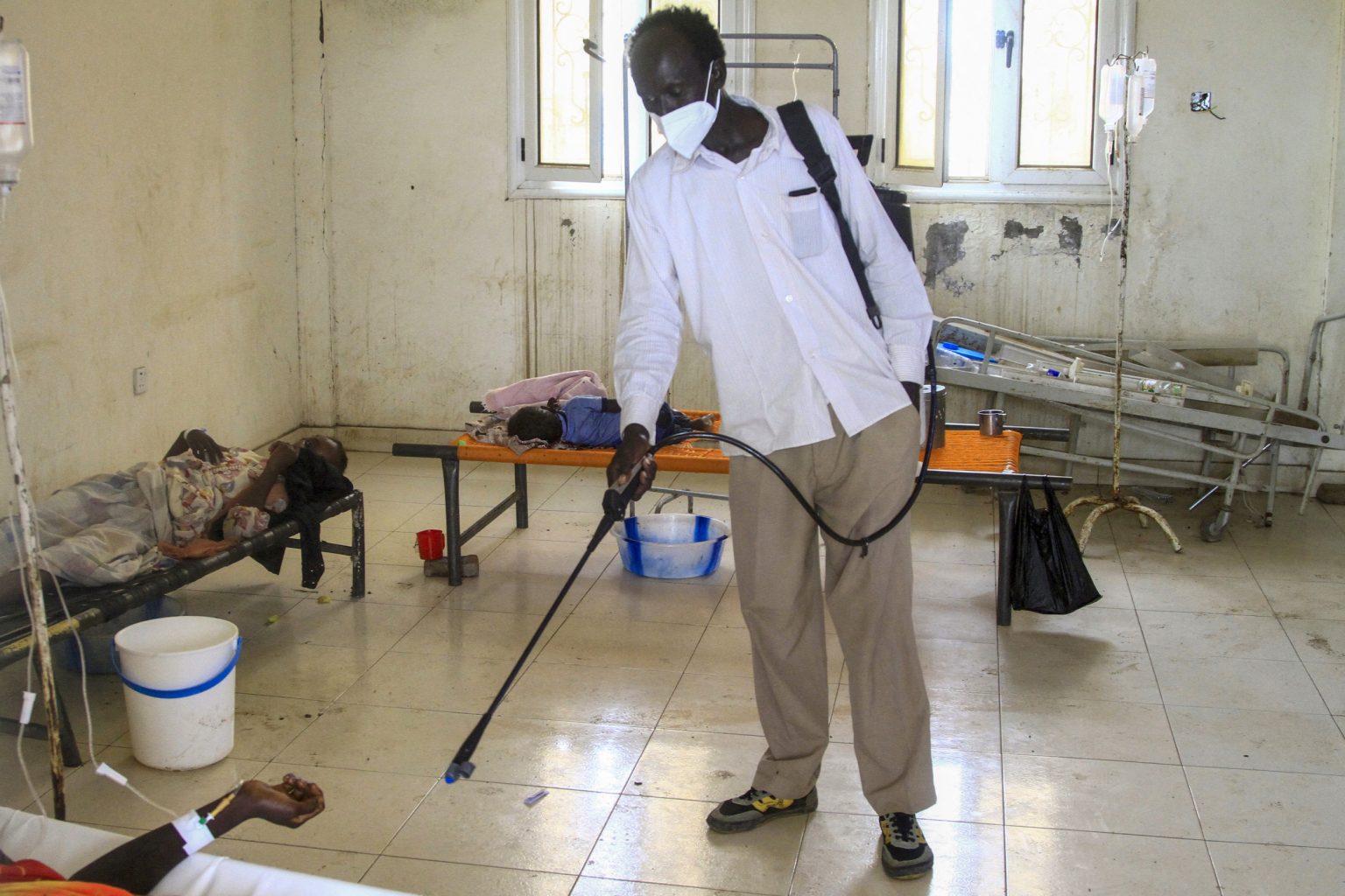 man disinfects hospital sudan