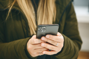 blonde girl holds phone triple camera