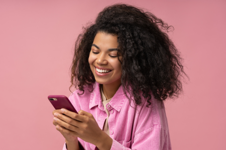 woman wearing pink shirt smiles holding phone