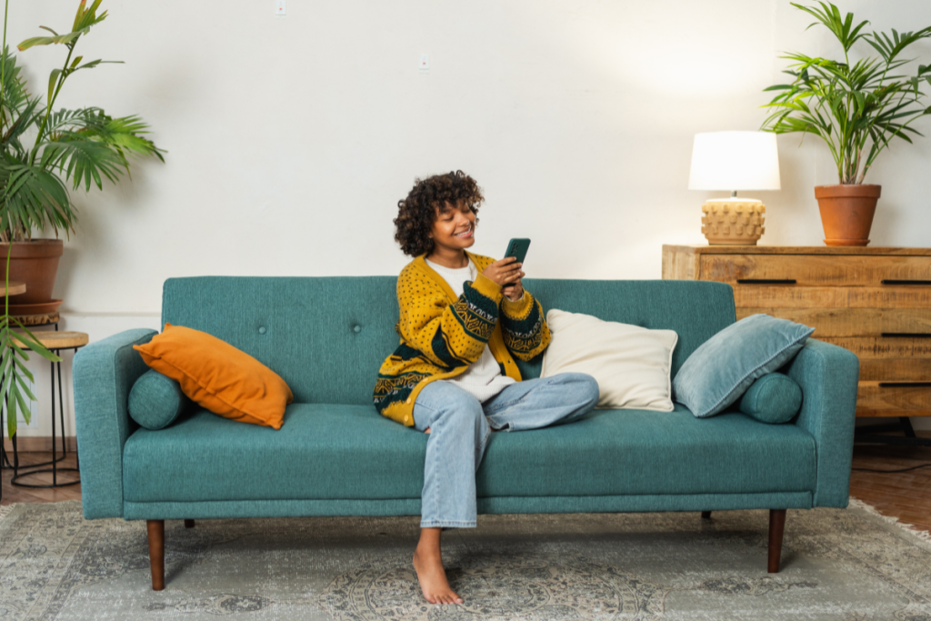 woman smiles holding cell phone blue couch