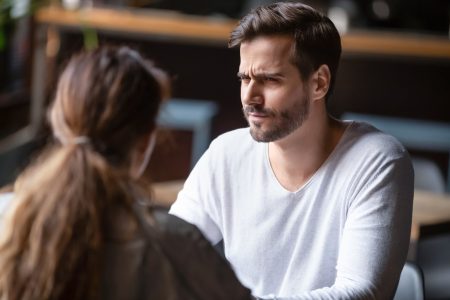 man looks unhappy while woman talks