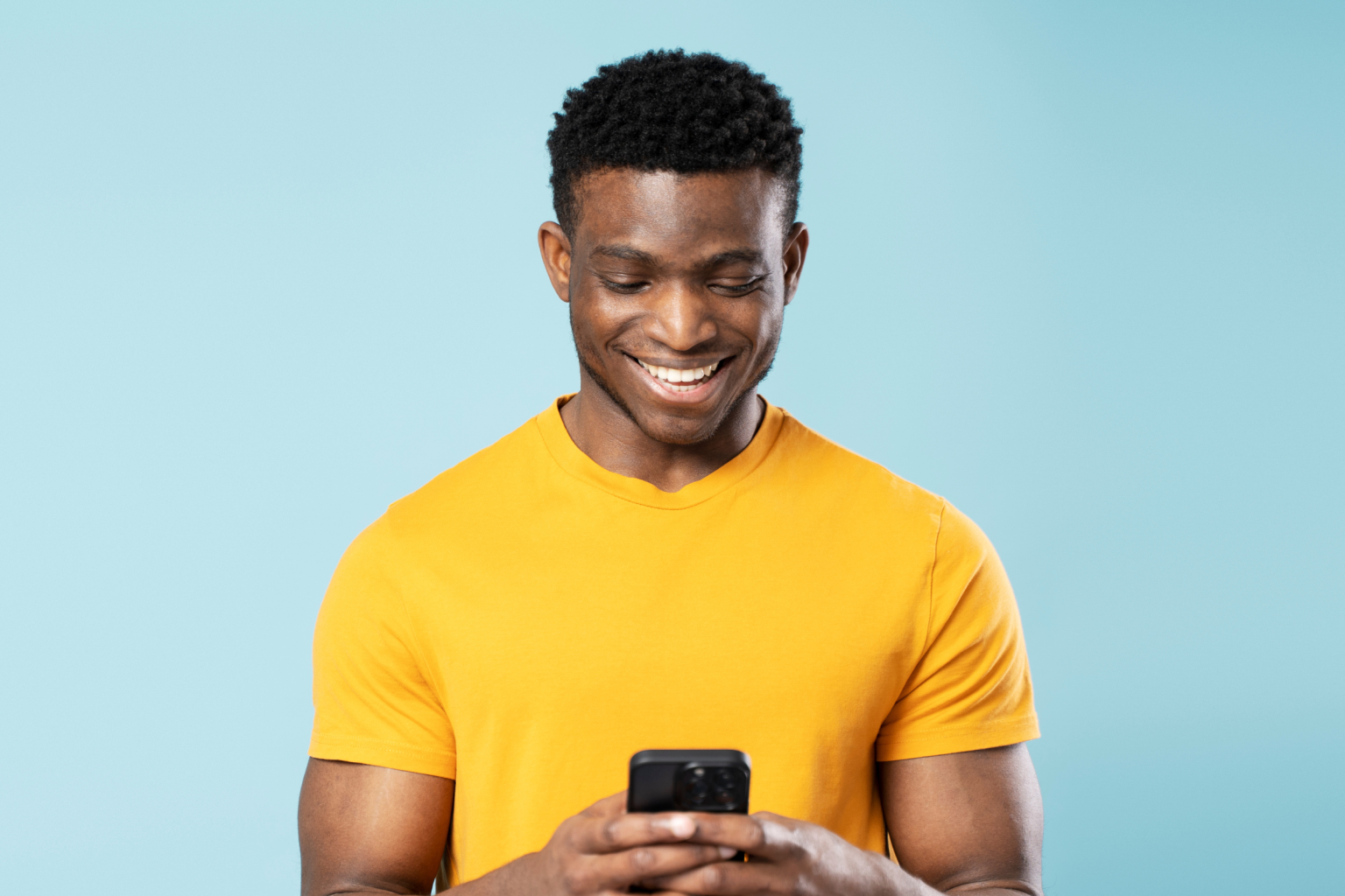 man yellow shirt blue background smiles phone