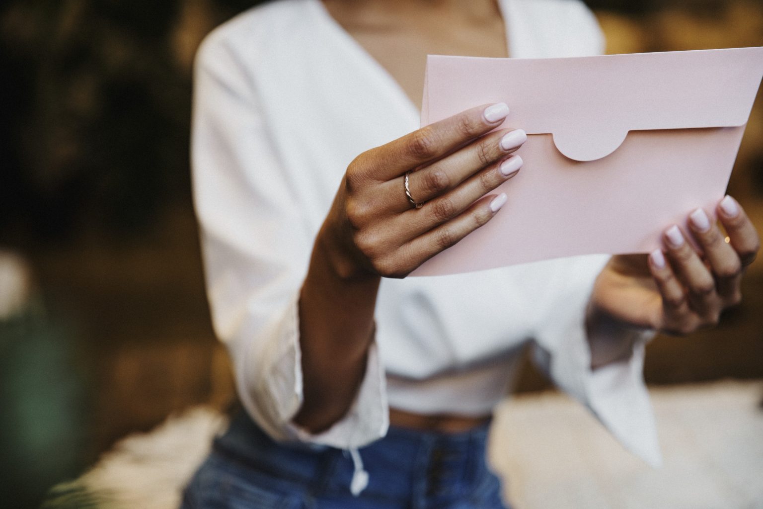 woman holds wedding invite pink