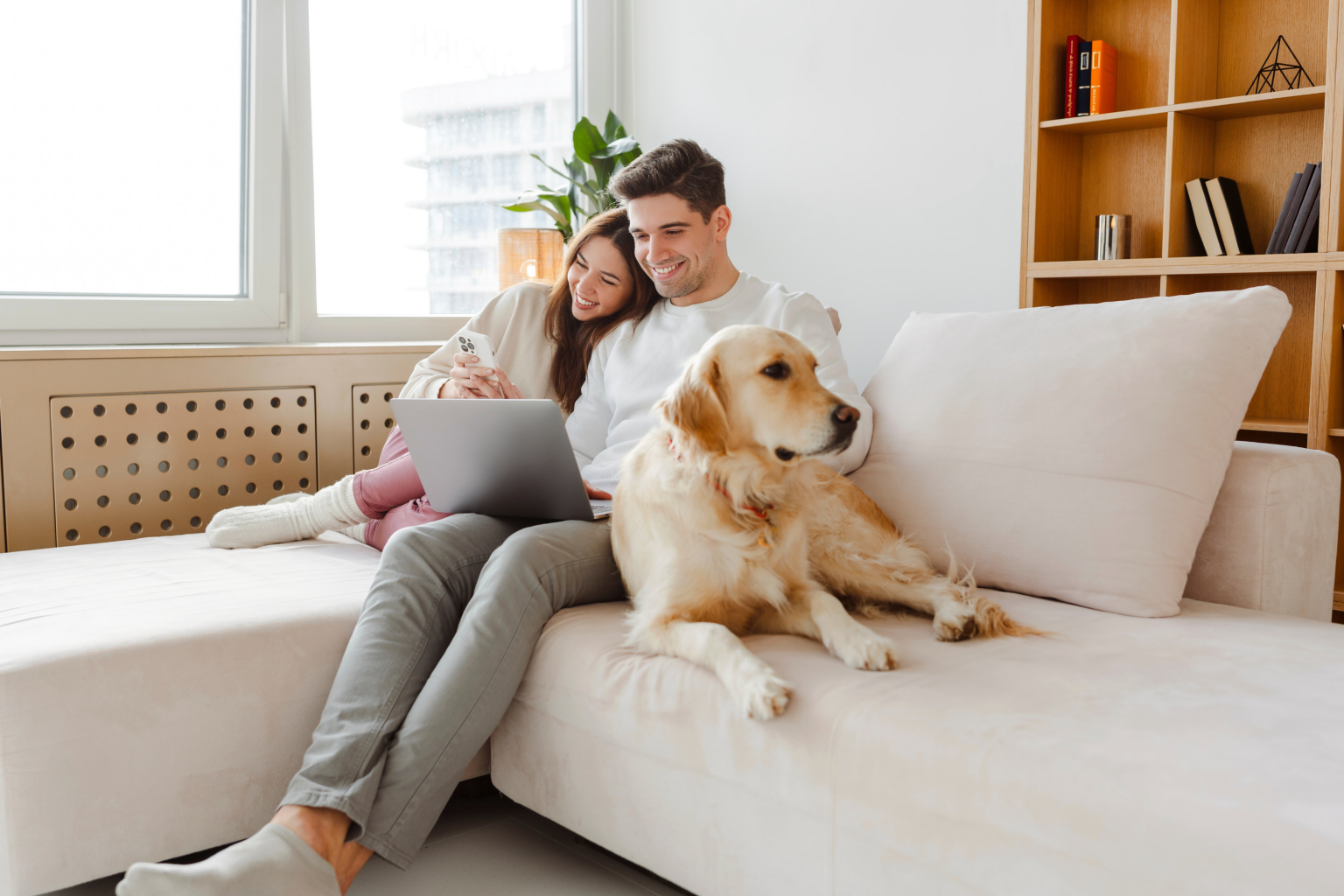 happy couple dog sofa mobile phone laptop