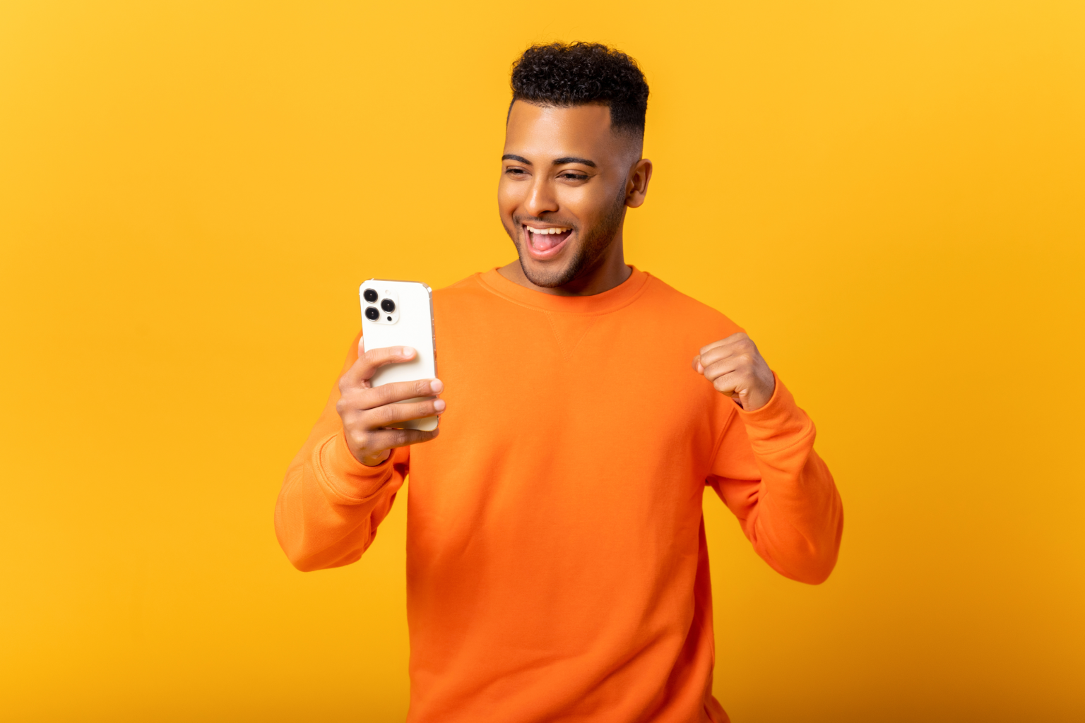 man orange shirt yellow background cell phone