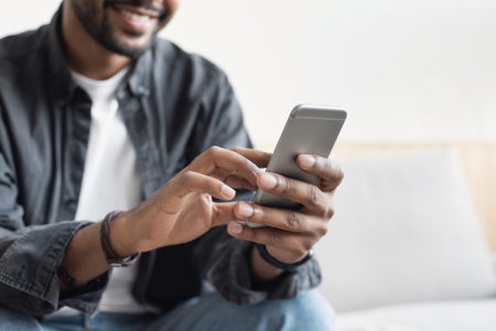 man wearing jeans button down smiles mobile phone