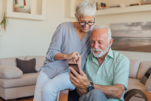 older couple hold hands mobile phone home