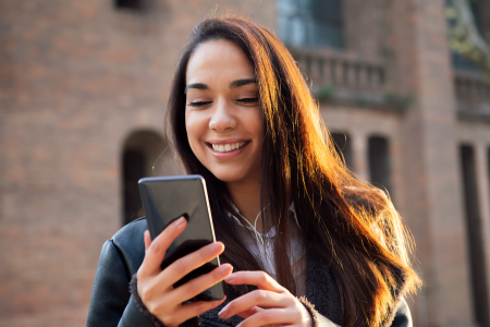 woman long hair smiles mobile phone street