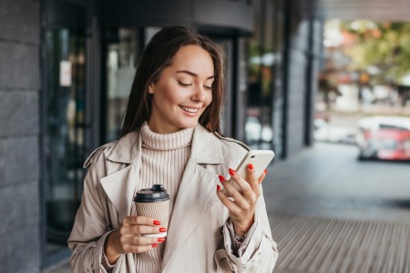 woman painted nails holds coffee cell phone