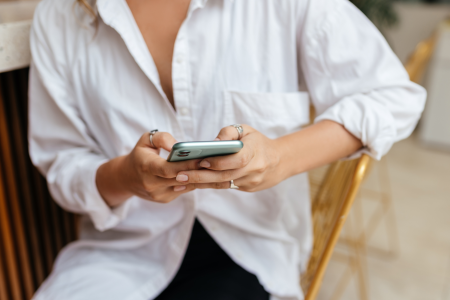 woman white shirt sits table mobile phone