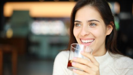 smiling woman drinking soda in glass