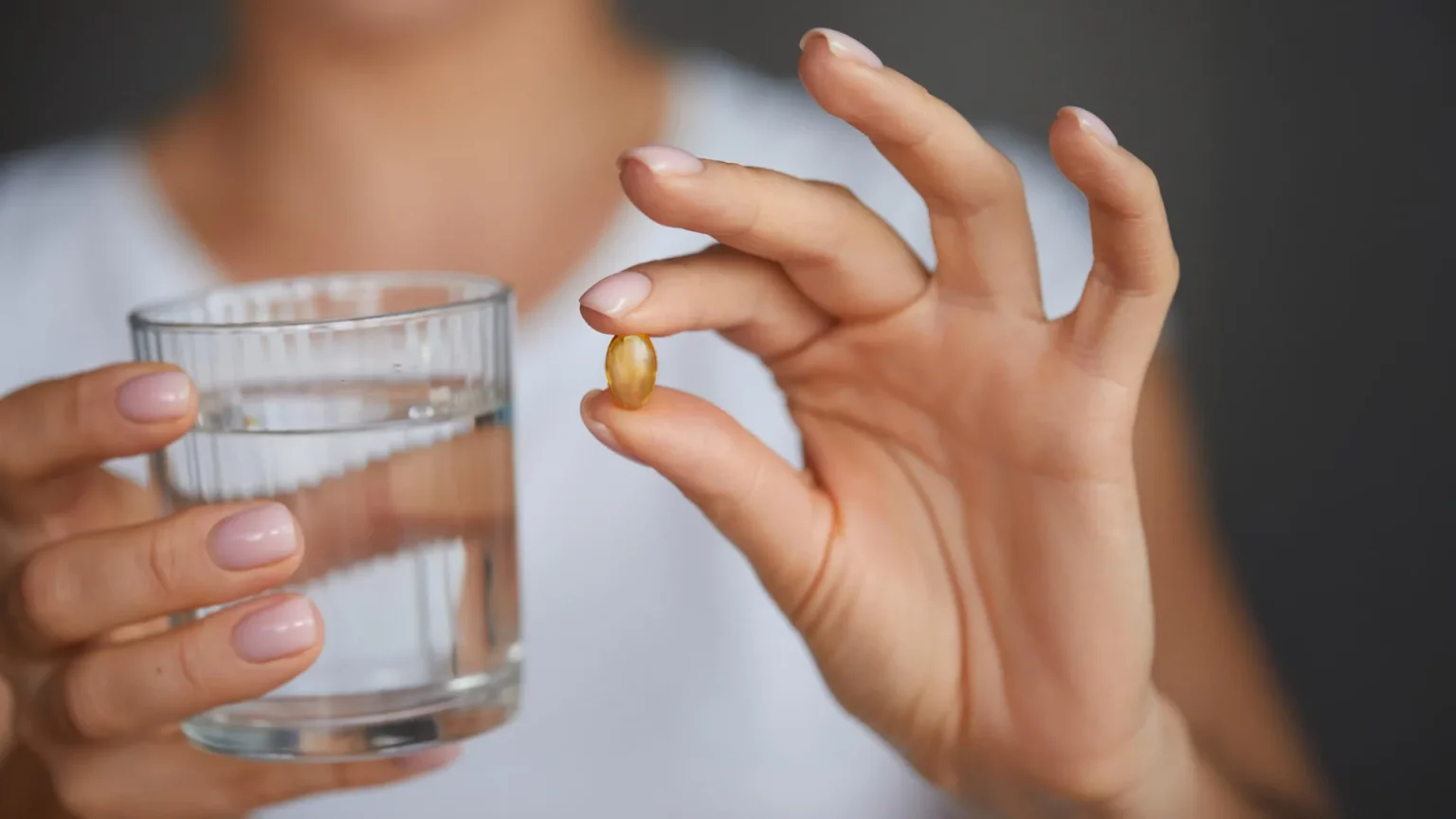 woman holding vitamin d omega 3 supplement capsule.webp