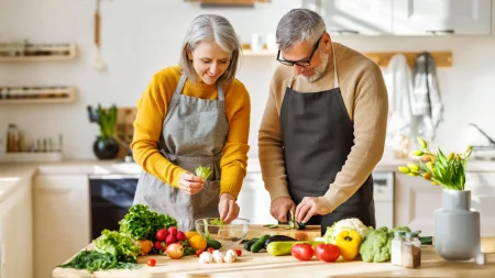 Array senior couple in kitchen preparing healthy salad.webp