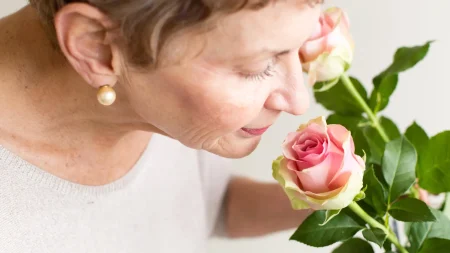 senior woman smelling pink rose.webp